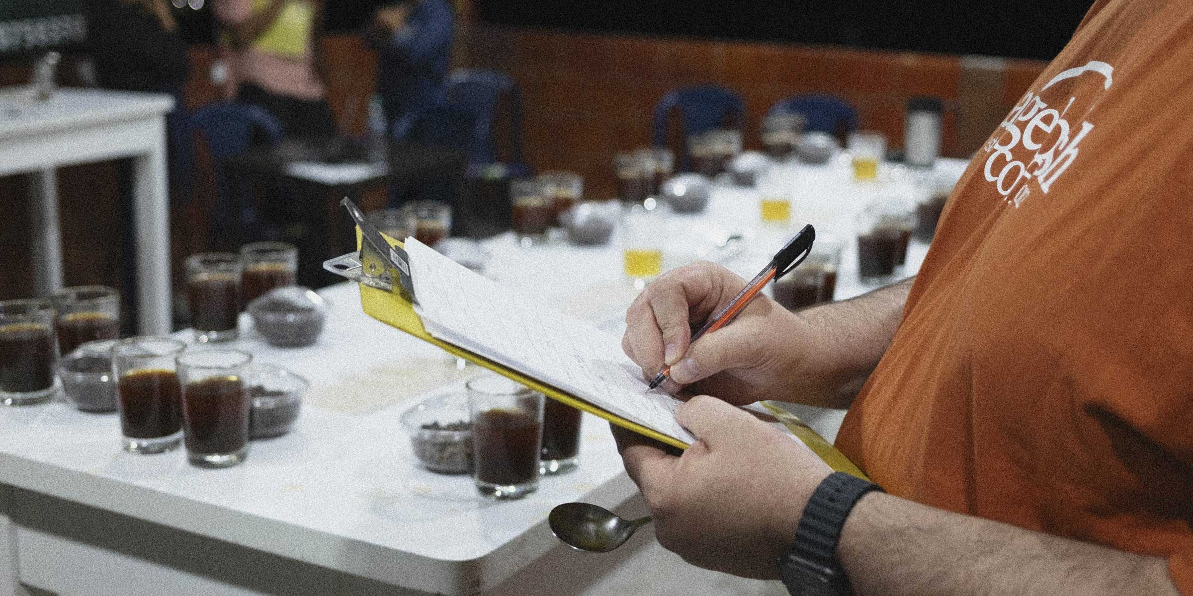 Someone taking notes about coffee during a coffee cupping
