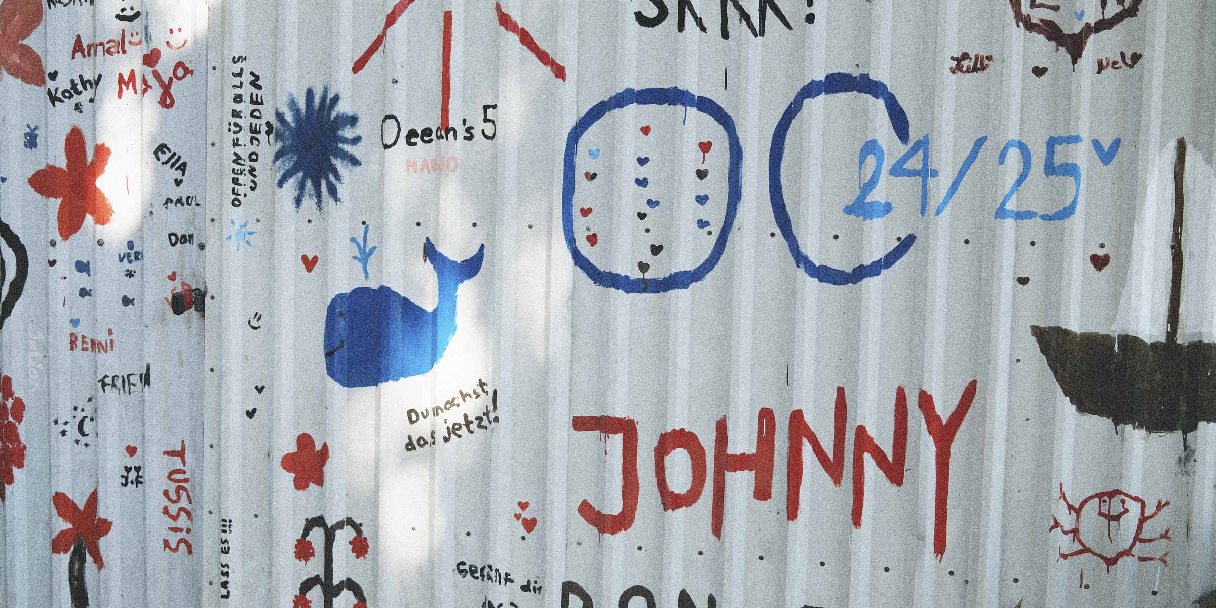 The side of a barn with writing and drawings on it