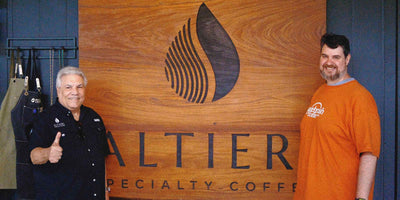 Eugene and Matt posing in front of a wooden sign that says Altieri Specialty Coffee