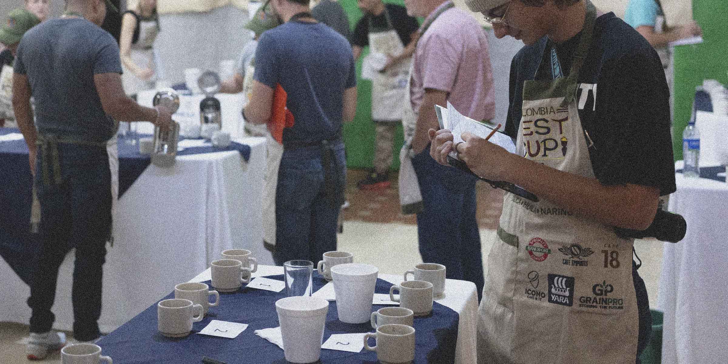 Noah in a white apron assessing quality of specialty coffee during a cupping competition