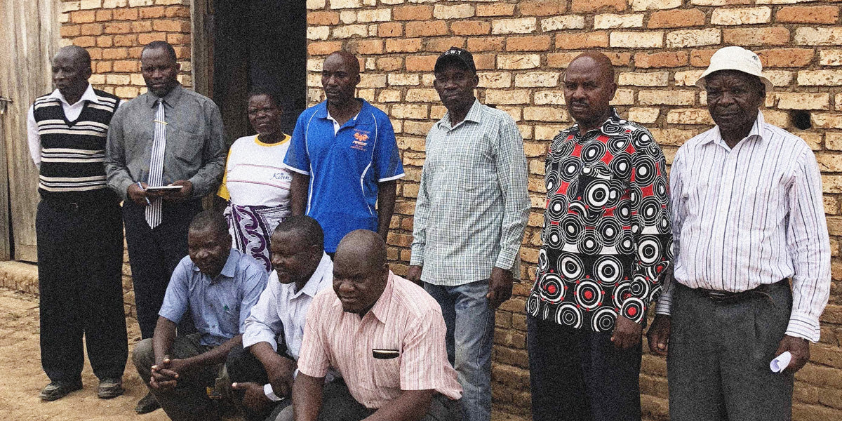 Group of people standing in front of a brick wall at a specialty coffee farm