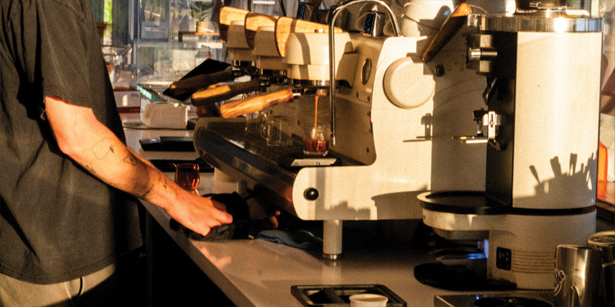 Person operating an espresso machine on a specialty coffee bar