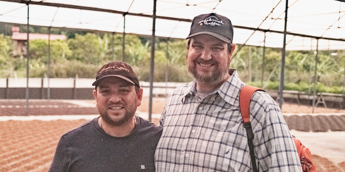 Ivan and matt standing together in front of a specialty coffee patio for drying coffee