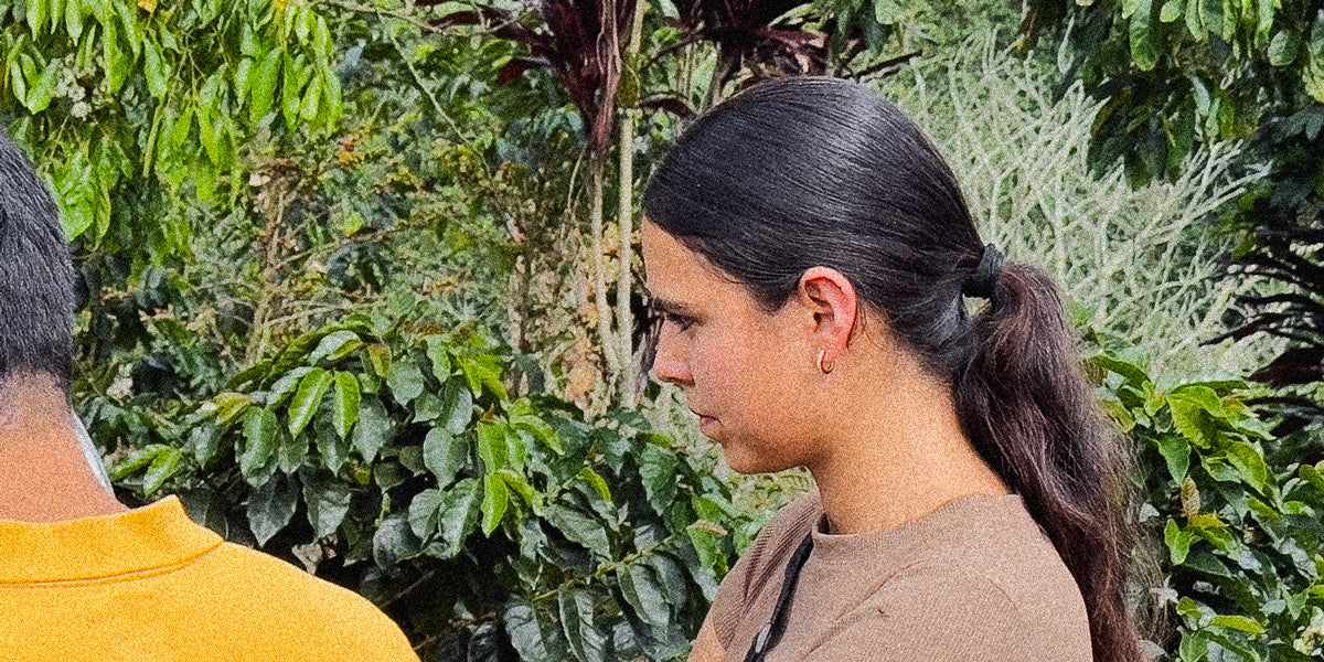 Natalia standing in her farm assessing coffee plants