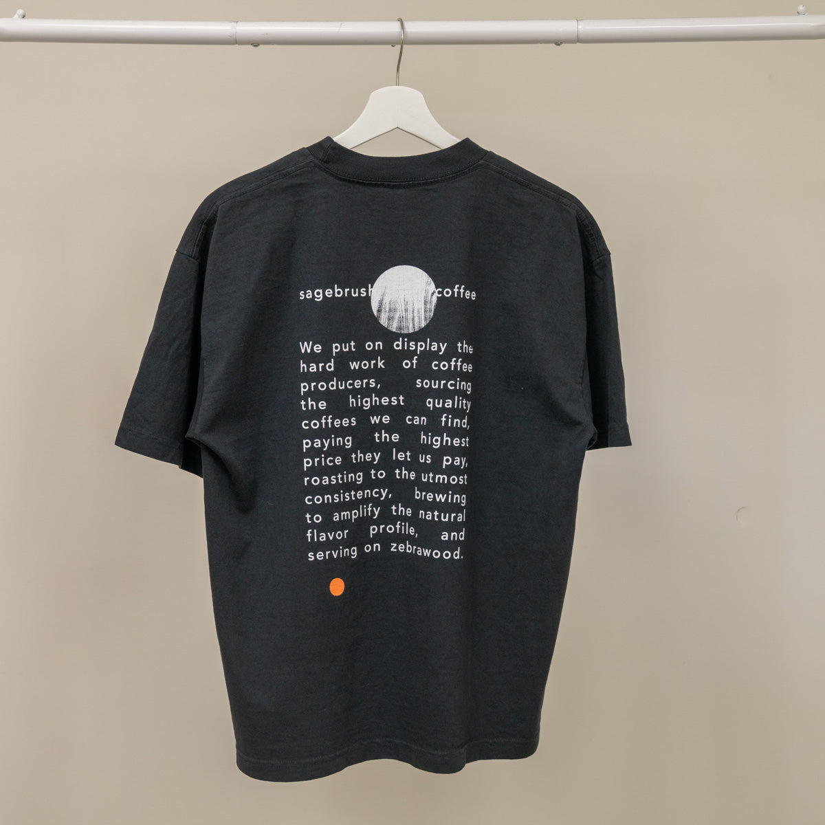 Black t-shirt with white text and a logo on a beige background