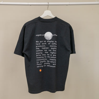 Black t-shirt with white text and a logo on a beige background