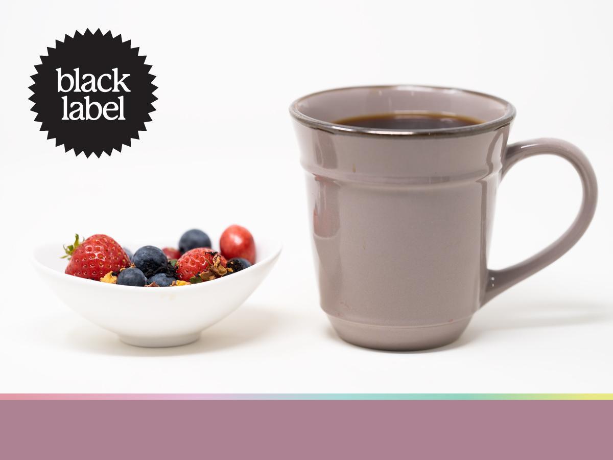 A cup of coffee next to a bowl of mixed berries and flower petals (flavor notes)
